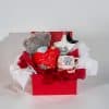 Valentine luxury gift box with teddy bear, love message heart, romantic mug, chocolates and decorative items in red and white packaging on a neutral background