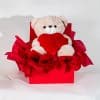 Valentine gift box with teddy bear holding red heart in elegant red romantic packaging on a neutral background