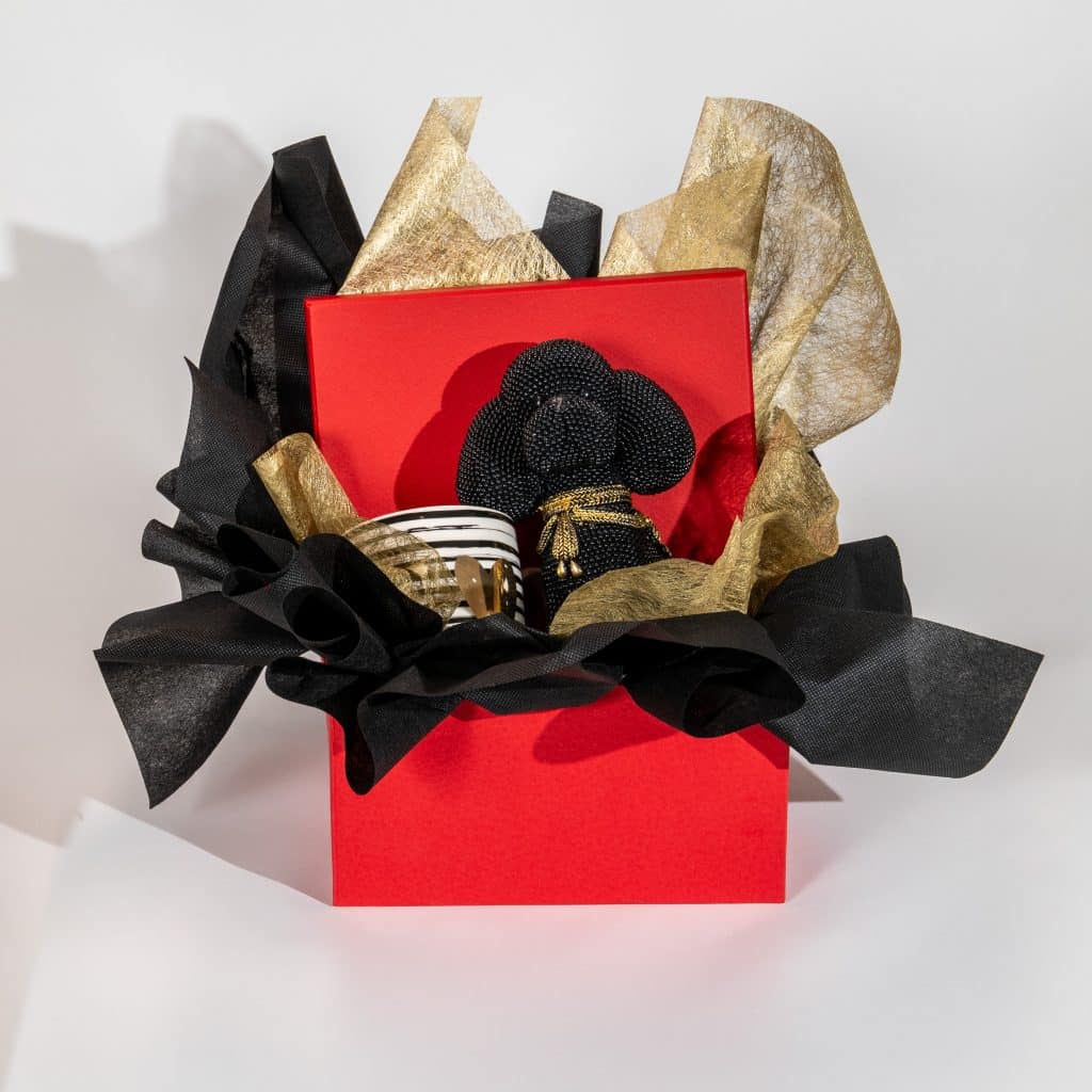 Valentine luxury gift box with black teddy bear, love mug and black gold elegant wrapping in red gift box on a neutral background