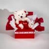 Valentine gift box with teddy bear holding I Love You heart and heart pattern mug in red and white romantic packaging on a neutral background