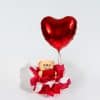 Valentine gift box with teddy bear holding heart and large red heart foil balloon in luxury red and white romantic packaging on neutral background