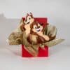 Valentine gift box with cute squirrel couple figurines in elegant red and gold romantic packaging on neutral background