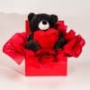 Valentine gift box with black teddy bear holding red heart in elegant red romantic packaging on neutral background
