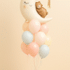 Balloon bouquet with a large crescent moon foil balloon featuring a bear, surrounded by pastel pink, mint, peach, and yellow latex balloons, with a matching pastel-colored balloon base.