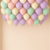 Loose assorted macaron latex balloons floating at the ceiling with long curling ribbons, creating a soft and playful party decor effect.