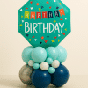 Teal “Happy Birthday” foil balloon with confetti pattern on a base of aqua, navy, silver, and white balloons — a fun and festive birthday balloon tower.