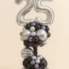 Balloon column featuring large silver foil number balloons "25", black spiral pole, and clusters of black, silver, and lilac balloons, including a birthday message balloon.