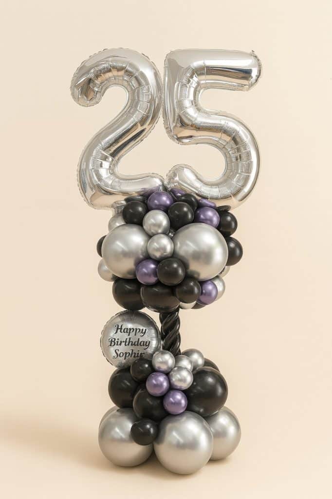 Balloon column featuring large silver foil number balloons "25", black spiral pole, and clusters of black, silver, and lilac balloons, including a birthday message balloon.