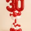 Balloon column featuring large red foil number balloons “3” and “0” on a red and white base with a twisted red balloon stem.