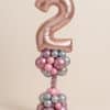 Balloon tower with rose gold number 2 foil balloon, standing on a pink and silver base with a pastel twisted stem and shiny chrome accents.