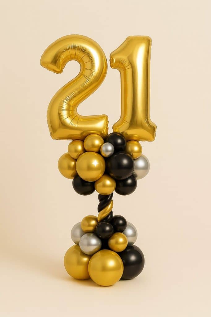 Balloon tower featuring gold foil number 21 balloons, standing on a base of black, gold, and silver balloons with a twisted black-and-gold stem.