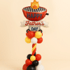 Balloon tower with BBQ grill “Happy Father’s Day” foil balloon on a red, yellow, black, and white twisted balloon column and base.