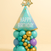 Birthday balloon bouquet with party hat foil, golden stars, and teal-gold balloon base.