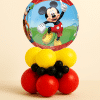 Mickey Mouse orb foil balloon table centerpiece with red yellow and black latex balloon base on neutral background