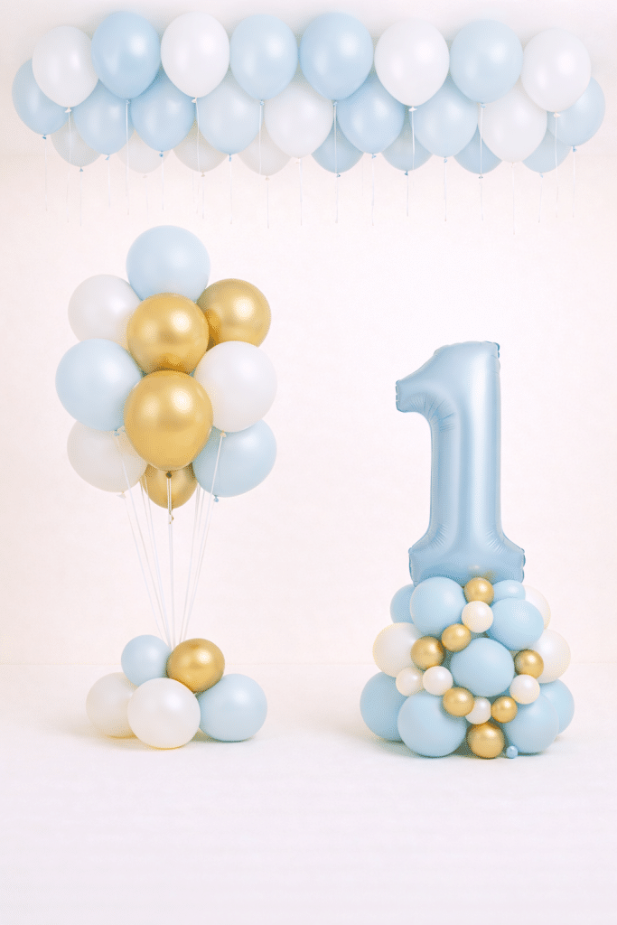 Light blue number one balloon tower with matching blue white and gold bouquet and loose blue and white ceiling balloons