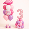 Pastel pink and lavender flamingo birthday balloon set with custom number column and matching Happy Birthday flamingo bouquet on floor standing bases