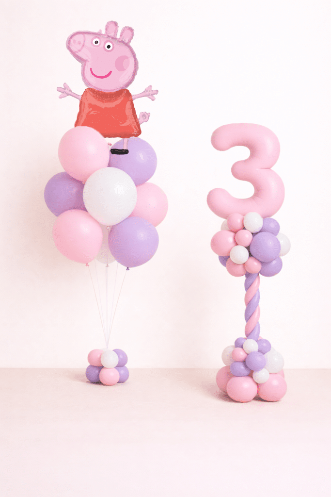 Peppa Pig birthday balloon duo with pastel pink number twisted column and matching pink and lavender latex bouquet in neutral studio background