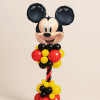 Mickey head foil balloon tower with red and black spiral column and red, yellow and black balloon base on a neutral background.