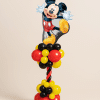 Mickey Mouse foil balloon on a red, yellow and black spiral balloon column with layered balloon base on a neutral background.