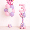 Pastel pink and lavender Stitch birthday balloon set with helium bouquet and twisted number column on a neutral background.