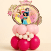 Disney Princess crown foil balloon on a pink and red latex balloon table centerpiece with small decorative balloon accents on a neutral background.