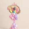Disney Princess crown foil balloon on a pastel pink, lavender, and white twisted balloon column with decorative base on a neutral background.