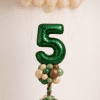 Safari jungle birthday balloon display with green foil number column, beige ceiling balloon cloud and matching loose helium balloons in green brown neutral tones