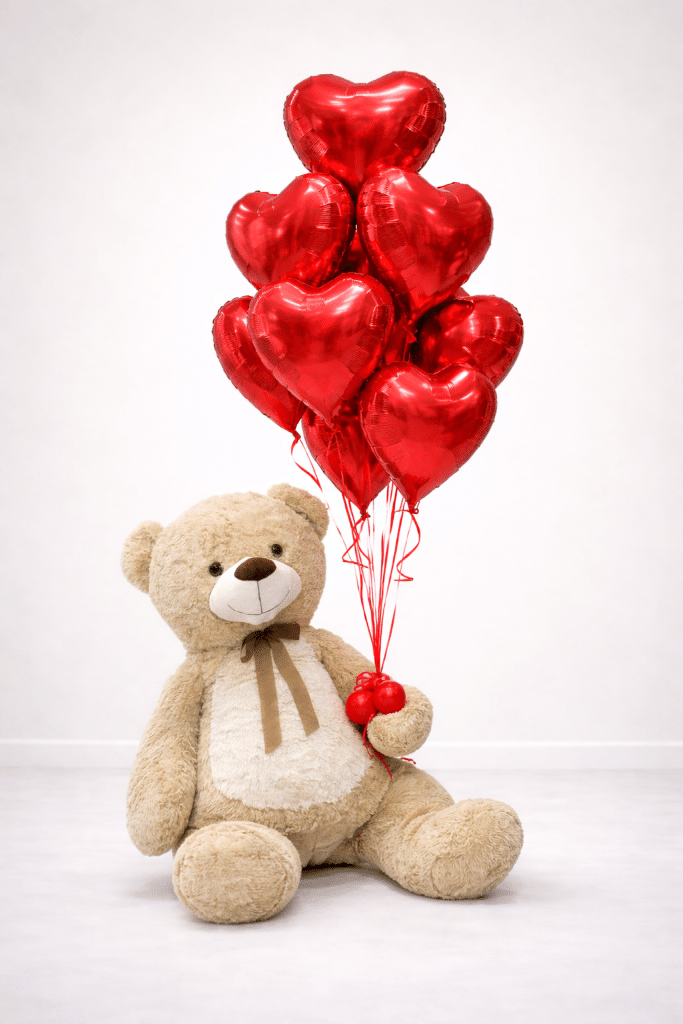 Giant teddy bear holding a bouquet of red helium heart balloons on a soft neutral background, romantic Valentine’s balloon gift arrangement.