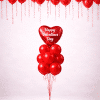Valentine’s Day balloon column with red heart foil balloon and red latex balloon cluster, combined with floating red ceiling balloons and hanging ribbons on a neutral background.
