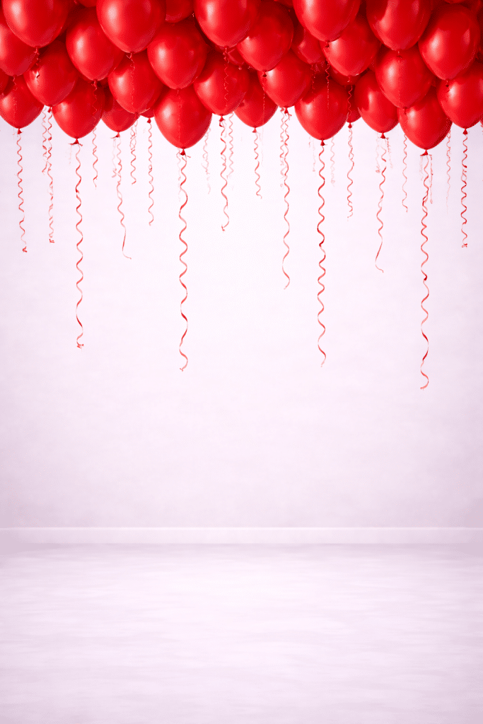 Romantic ceiling decoration with red helium balloons and long curly ribbons hanging down, creating a floating balloon canopy against a soft neutral background.