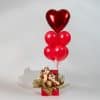 Red heart balloon bouquet rising from a decorative gift box with cute character figures and red helium balloons on a neutral background.