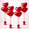 Set of four Valentine’s Day balloon bouquets with red heart-shaped foil balloons, red curling ribbons, and matching weighted bases on a neutral background.