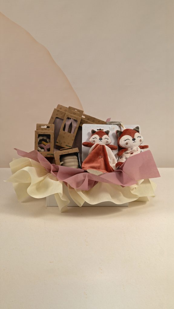 Fox-themed baby gift box with fox comforter and soft toy, silicone bib, cup, cutlery and teether, presented with ivory and dusty rose wrapping.
